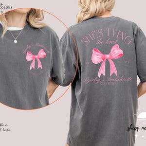 a woman wearing a gray shirt with a pink bow