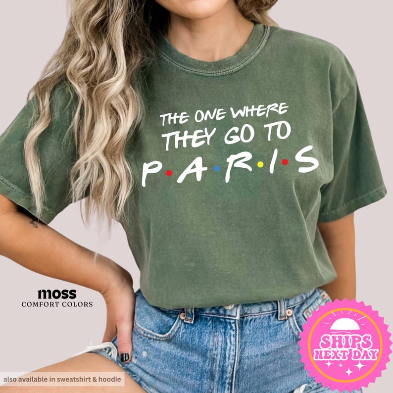 May include: Green t-shirt with the text "The One Where They Go To Paris" in white with colorful dots. The shirt is a comfort color and is available in sweatshirt and hoodie styles.
