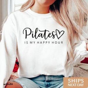 a woman wearing a sweatshirt that says pilates is my happy hour