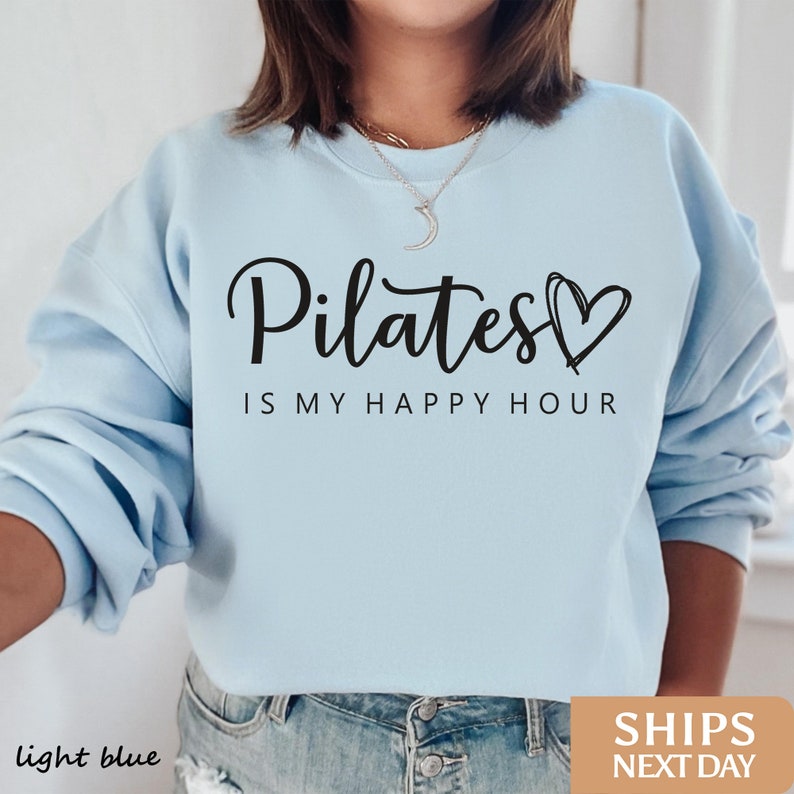 a woman wearing a sweatshirt that says pilates is my happy hour