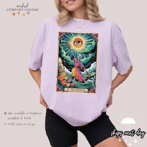 a woman wearing a purple t - shirt with a picture of a woman holding a