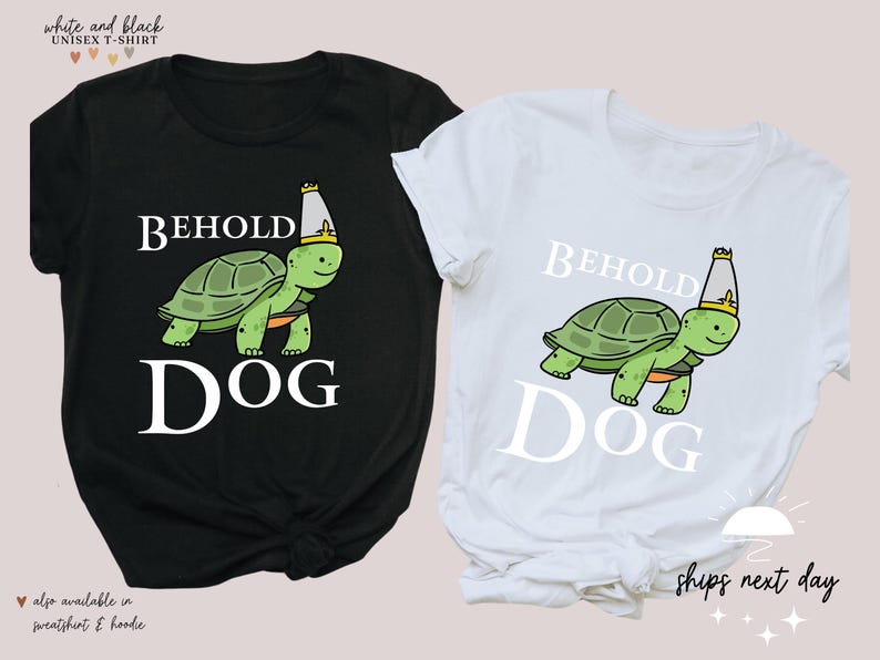 May include: Two t-shirts featuring a graphic of a turtle wearing a crown and the text "Behold Dog". One shirt is black and the other is white.