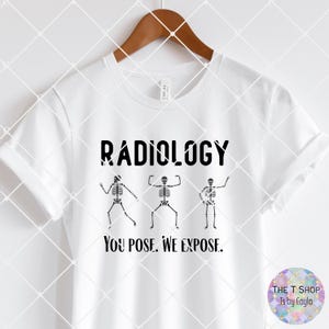 May include: White t-shirt with the word "RADIOLOGY" in black block letters above three dancing skeleton figures. Below the skeletons, the text reads "YOU POSE. WE EXPOSE."