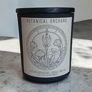 May include: Black candle jar with a white label that says "Botanical Orchard" and features a botanical illustration of flowers and plants. The label also says "Atrium Apothecary, Joshua Tree CA 200+g Soy Blend Candle".