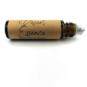 May include: A brown glass roller bottle with a silver roller ball. The bottle is labeled "Desert Essence Essential Oil Blend".