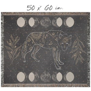 May include: A woven throw blanket with a dark gray background featuring a gold wolf silhouette with celestial and floral designs. The wolf is surrounded by a repeating pattern of gold moons and stars. The blanket measures 50 x 60 inches.