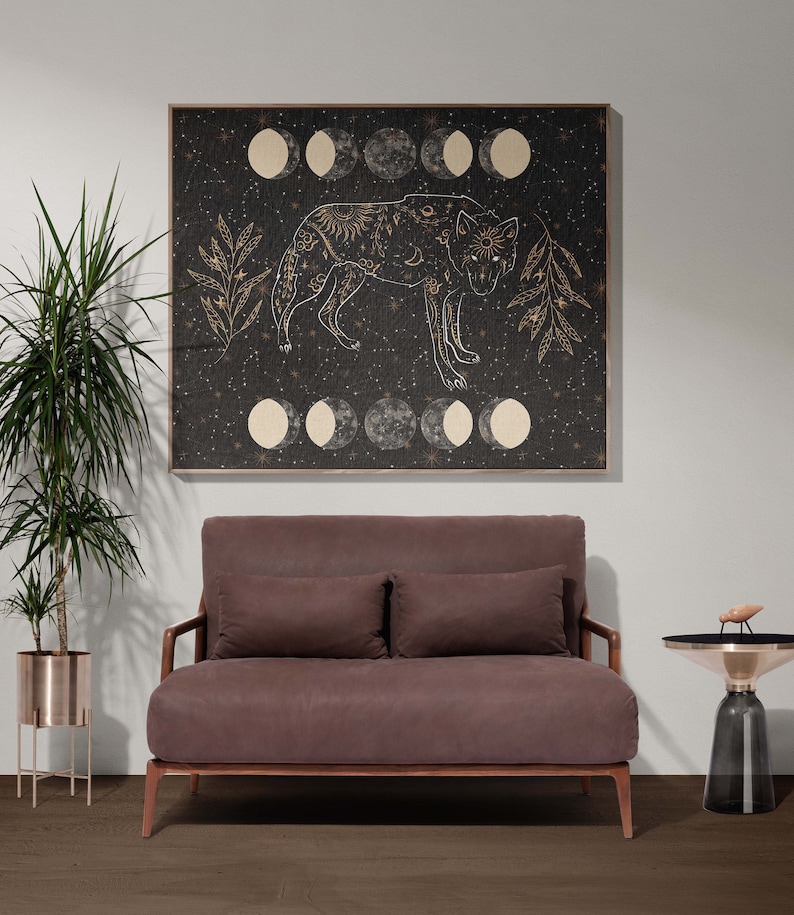 May include: A brown velvet loveseat with two pillows sits in front of a black and gold framed canvas print of a wolf with a moon and stars design. A small gold and black side table sits to the right of the loveseat.