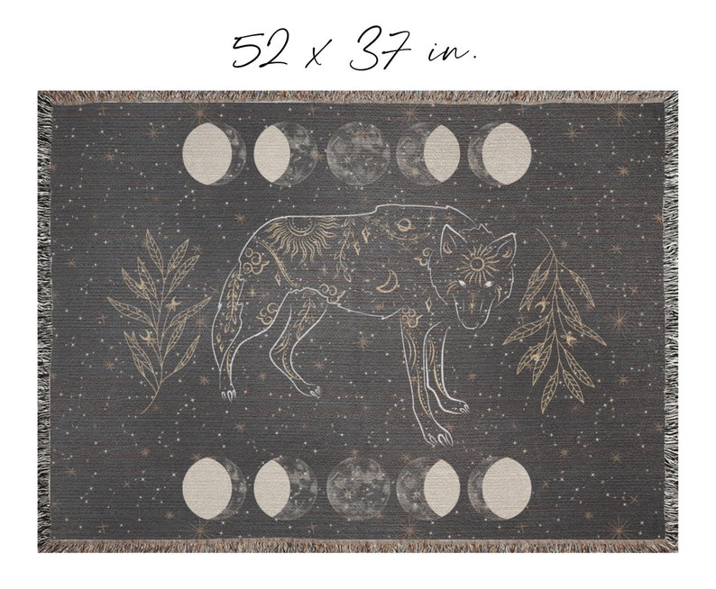 May include: A woven throw blanket with a dark gray background and a white wolf design. The wolf is surrounded by gold stars, moons, and leaves. The blanket measures 52 x 37 inches.
