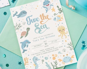 May include: A white invitation card with a blue and green ocean theme. The text reads "Two the Sea" and "Join us to celebrate Tom's 2nd Birthday". The card is decorated with sea creatures like a whale, shark, octopus, turtle, dolphin, and a seahorse.