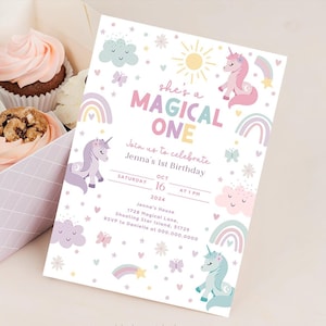 Może przedstawiać: Kolorowe zaproszenie na pierwsze urodziny z motywem jednorożca. Zaproszenie zawiera tęczę, gwiazdy, chmury, motyle i tekst "She's a Magical One".