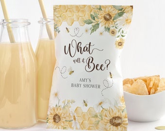 May include: A baby shower-themed snack bag with the text "What will it Bee?" and floral and honeycomb designs. The bag is next to two glass bottles of juice with straws and a bowl of chips.