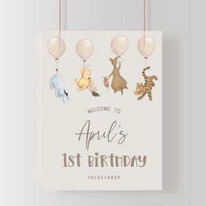 K&ouml;nnte beinhalten: Ein Winnie-the-Pooh-Geburtstagsschild mit wei&szlig;em Hintergrund und braunem Text. Das Schild lautet "Willkommen zu Aprils 1. Geburtstag 10/05/2024". Es gibt f&uuml;nf Ballons und f&uuml;nf Figuren aus Winnie-the-Pooh, darunter Tigger, Ferkel, Esel und Winnie-the-Pooh.