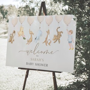 Peut inclure: Une pancarte d'accueil blanche avec Winnie l'ourson et ses amis tenant des ballons. La pancarte indique "Bienvenue au baby shower de Sarah".