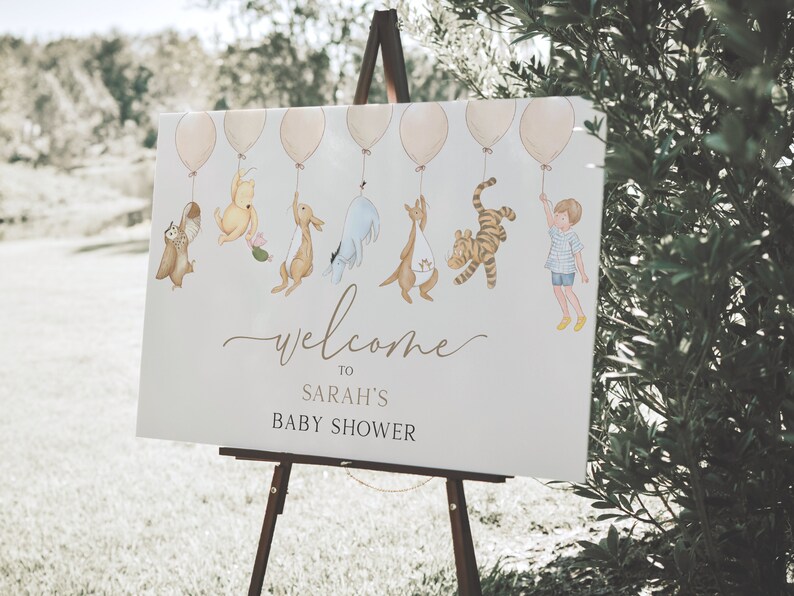 Peut inclure: Une pancarte d'accueil blanche avec Winnie l'ourson et ses amis tenant des ballons. La pancarte indique "Bienvenue au baby shower de Sarah".
