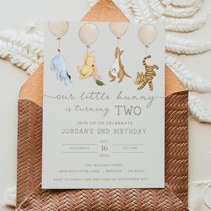 Puede incluir: Una invitación de cumpleaños con temática de Winnie the Pooh con un fondo gris claro. La invitación presenta una ilustración de dibujos animados de Winnie the Pooh, Piglet, Tigger y Eeyore sosteniendo globos. El texto de la invitación dice "our little hunny is turning TWO" y "JOIN US TO CELEBRATE JORDAN'S 2ND BIRTHDAY". La fecha y hora de la fiesta se enumeran como "SATURDAY OCT 16 2024 AT 1 PM". La ubicación se enumera como "THE WILSON'S HOME 1093 MISTLETOE LANE REDDING CA 90241". La información de RSVP se enumera como "RSVP TO HINDY 000 000 0000 BY SEPTEMBER 21ST".