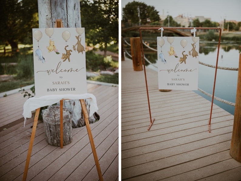 Op de afbeelding: Twee welkomstborden voor een babyshower met een Winnie de Poeh-thema. De borden bevatten illustraties van Winnie de Poeh, Biggetje, Tijger en Eeyore. E&eacute;n bord staat op een ezel en het andere op een koperen standaard.