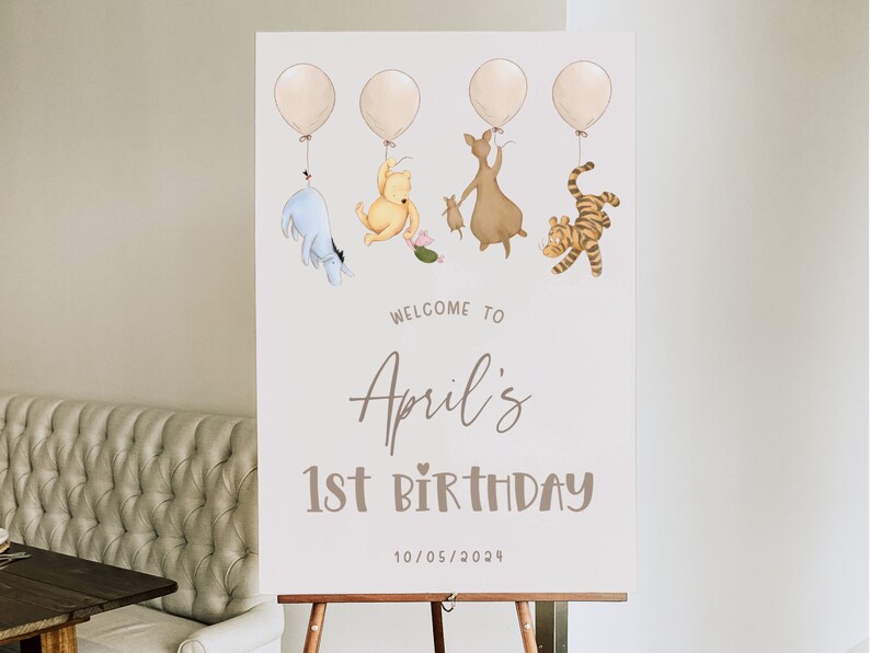 K&ouml;nnte beinhalten: Ein Willkommens-Schild zum 1. Geburtstag im Winnie-Puuh-Stil. Das Schild zeigt Winnie Puuh, Ferkel, Tigger und Esel, die an Ballons festhalten. Auf dem Schild steht "Willkommen zu Aprils 1. Geburtstag 10/05/2024".