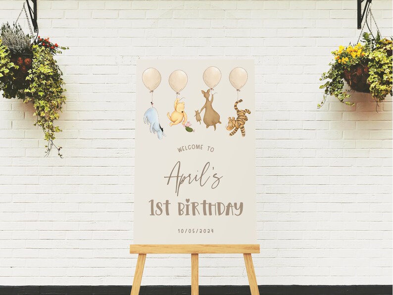K&ouml;nnte beinhalten: Ein Winnie Puuh-Motto-Schild f&uuml;r eine 1. Geburtstagsparty mit Ballons, Winnie Puuh, Ferkel, Esel und Tiger. Das Schild lautet "Willkommen zu Aprils 1. Geburtstag 10/05/2023".