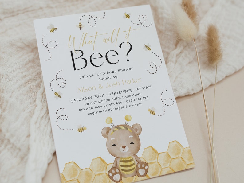 May include: A white baby shower invitation with a cute cartoon bear wearing a bee costume. The invitation says "What will it Bee?" and includes details about the shower, including the date, time, location, and RSVP information.
