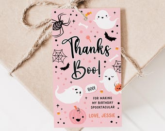 Może przedstawiać: Różowa etykieta prezentowa na Halloween z napisem "Thanks Boo!" i ilustracjami duchów, nietoperzy, pająków i dyni. Etykieta zawiera tekst "For making my birthday spooktacular. Love, Jessie."