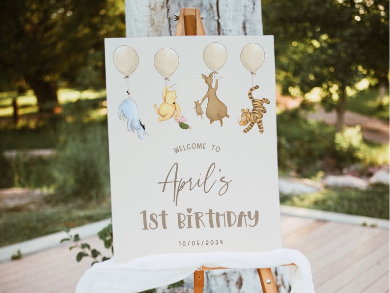 K&ouml;nnte beinhalten: Ein Winnie-the-Pooh-Geburtstagsschild mit f&uuml;nf gelben Ballons, einem blauen Esel, einem gelben B&auml;ren, einem braunen K&auml;nguru und einem orangefarbenen Tiger. Das Schild lautet "Willkommen zum 1. Geburtstag von April 10/05/2024".