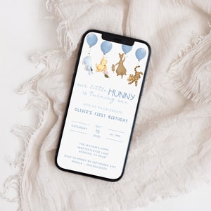 May include: A blue and white digital invitation for a first birthday party. The invitation features Winnie the Pooh characters, including Piglet, Eeyore, Tigger, and Pooh Bear, holding blue balloons. The text on the invitation reads "our little HUNNY is turning one" and "Oliver's First Birthday". The date and time of the party are listed as "Saturday, October 15, 2022 at 1PM".