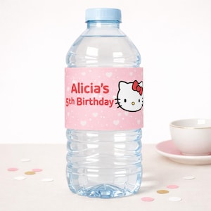 Peut inclure: Une bouteille d'eau en plastique transparent avec un bouchon bleu clair. La bouteille porte une étiquette rose avec le texte "Alicia's 5th Birthday" et une image de dessin animé de Hello Kitty. L'étiquette est ornée de coeurs blancs.