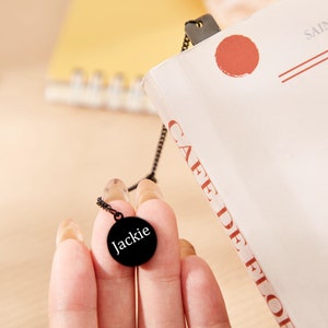 May include: A black necklace with a round pendant that says "Jackie" in white lettering.