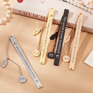 May include: Five gold, silver, and black metal bookmarks with engraved text and a dangling feather charm. The bookmarks have a chain attached to a round charm with a date engraved on it. The text on the bookmarks reads: "The world is your bookmark", "To many more chapters together", "When there's A Will, there's A Way", "Our story will always be my favorite", and "KS".