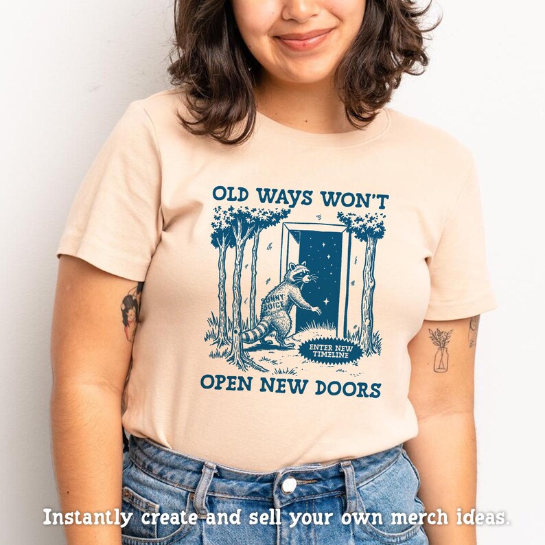 May include: A light beige t-shirt with a blue graphic of a raccoon opening a door with the text "Old ways won't open new doors".