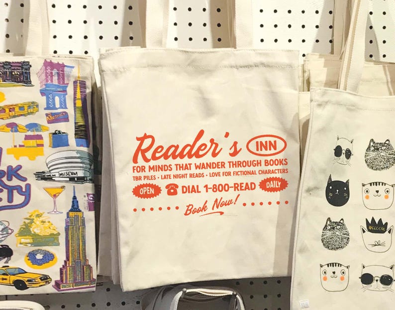 May include: White canvas tote bag with red text that reads "Reader's Inn" and "For minds that wander through books."  The bag also has a red phone icon and the text "Dial 1-800-READ".