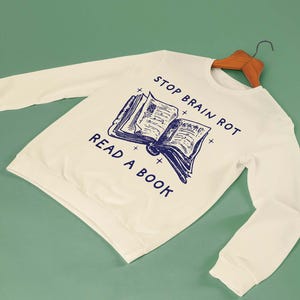 May include: A white sweatshirt with the text "Stop Brain Rot Read A Book" and a blue illustration of an open book.