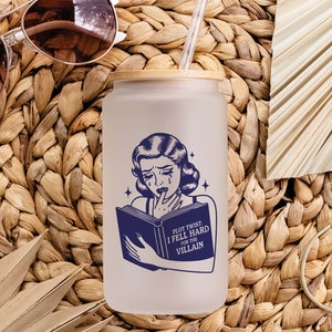 May include: A white reusable water bottle with a blue and white illustration of a woman reading a book. The text on the book reads "Plot Twist: I Fell Hard for the Villain".
