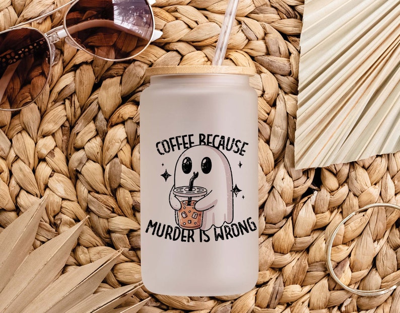 May include: A white ceramic mug with a black handle and the text "But First, Coffee" in a black, bold font. The mug is on a white surface. The mug is approximately 10 cm tall.