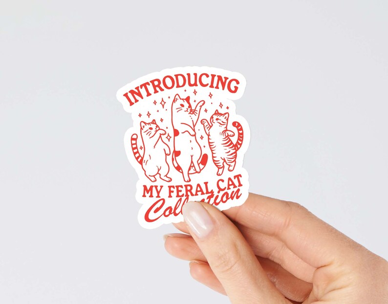 Puede incluir: Una pegatina blanca con texto rojo e ilustraciones de tres gatos bailando. El texto dice "Introducing My Feral Cat Collection."