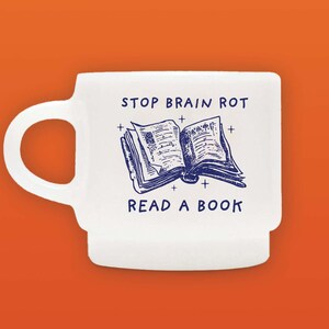 May include: White ceramic mug with a blue illustration of an open book and the text "STOP BRAIN ROT READ A BOOK".