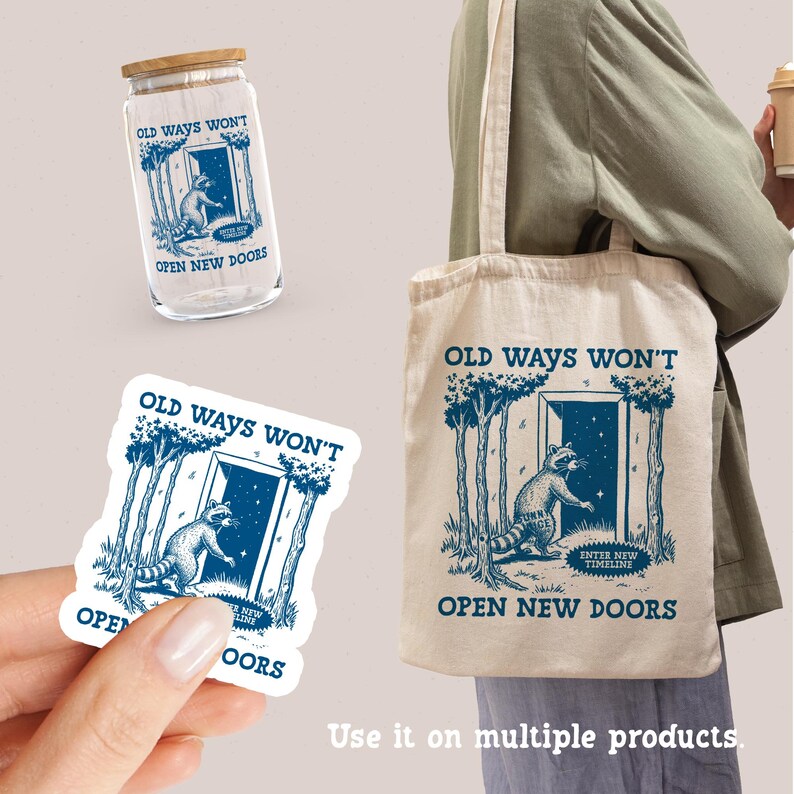 May include: A tote bag with a white background and blue text that reads "Old ways won't open new doors". The bag features a raccoon standing in front of a doorway with a starry sky behind it. The raccoon is holding a sign that reads "Enter new timeline".