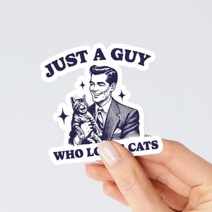 May include: A sticker featuring a vintage illustration of a man holding a cat. The text reads "Just a guy who loves cats".