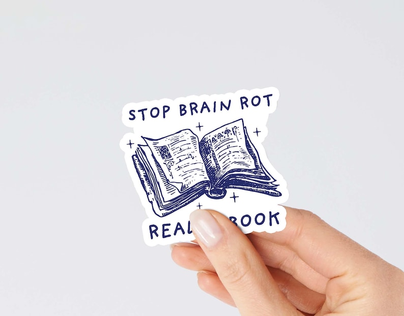 May include: White sticker with blue text and illustration. The text reads "Stop Brain Rot Read a Book". The illustration is of an open book with a blue outline.