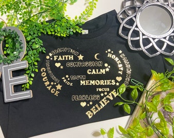 May include: Black t-shirt with a gold circle design featuring the words "Redemption", "Faith", "Compassion", "Truth", "Calm", "Memories", "Focus", "Fearless", "Believe", "Honesty", "Persistence", "Courage", and "Certainty".