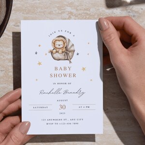 May include: Baby shower invitation featuring a watercolor illustration of a lion cub in a bassinet, surrounded by gold stars. The invitation includes the text "Baby Shower" and event details for Rachelle Brandry, August 30, 2025, at 4 PM.