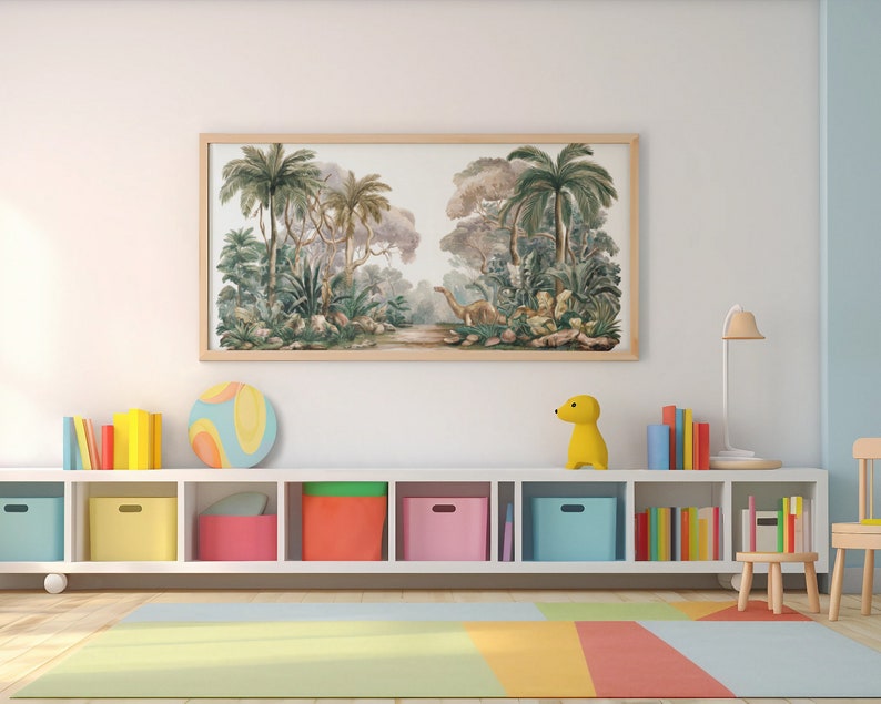 May include: A white bookshelf with six shelves filled with colorful books and toys. The top shelf has a framed print of a jungle scene with palm trees and a dinosaur. A yellow toy dinosaur sits on the shelf below the print.