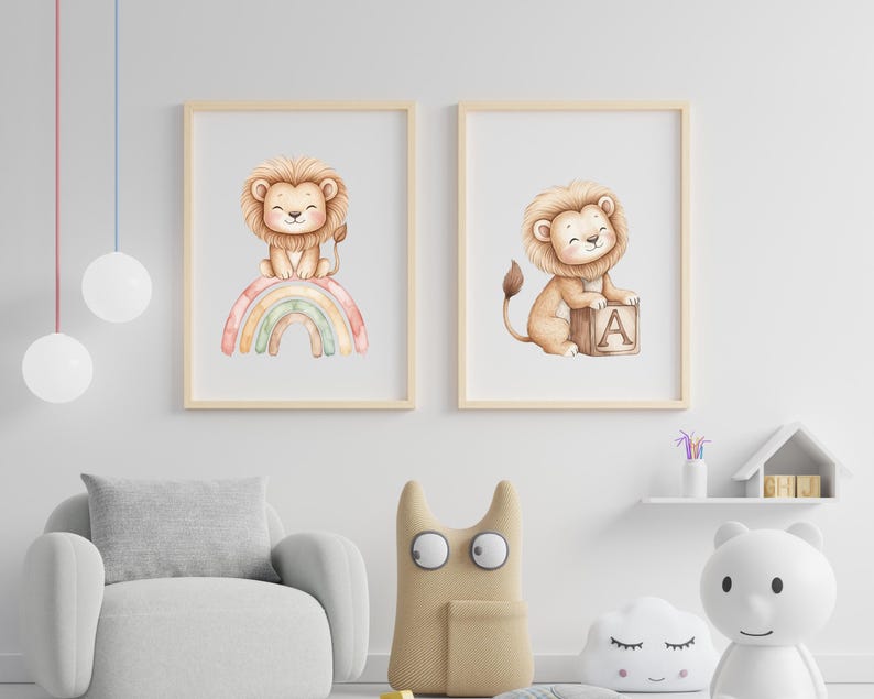 May include: Two framed watercolor prints featuring a lion cub. One sits atop a rainbow, the other with a block displaying the letter "A". The prints have light wood frames and are displayed in a nursery setting.