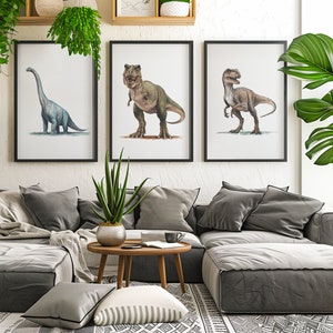 May include: Three framed illustrations of dinosaurs, a blue brachiosaurus, a green Tyrannosaurus Rex, and a brown velociraptor, hanging on a white wall above a gray sectional sofa with pillows and a coffee table.