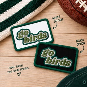 May include: Two rectangular embroidered patches featuring the text "go birds" in green with white outlines. One patch has a white background with a green border, and the other has a black background with a green border. Text on image: "WHITE OPTION", "BLACK OPTION", "SAME PATCH. TWO COLOR OPTIONS."