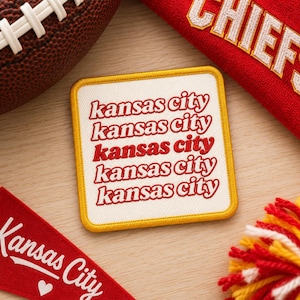 Puede incluir: Un parche cuadrado bordado con fondo blanco y borde amarillo. El texto "kansas city" se repite cinco veces en rojo, apilado verticalmente en una fuente estilizada e inclinada. El parche está rodeado de artículos relacionados con el fútbol.