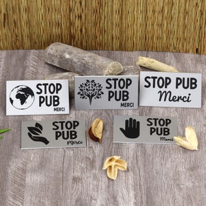 Peut inclure: Cinq plaques en métal argenté avec du texte et des graphismes noirs. Les plaques indiquent "Stop Pub Merci" avec différents graphismes, notamment un globe, un arbre, une main et des feuilles.