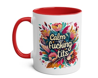 May include: White ceramic mug with a red interior and handle. The mug features a colorful floral design with the text "Calm your fucking tits" in a stylized font. The design includes shades of blue, yellow, pink, and green.