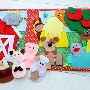 May include: A felt farm-themed finger puppet book with a red barn, a yellow hay bale, a green tree with red apples, and a variety of animal finger puppets including a cow, pig, lamb, chicken, dog, horse, and a duck.