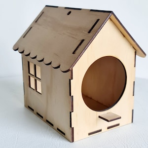May include: A wooden birdhouse with a round entrance hole and a small landing perch. The birdhouse has a scalloped roof and a small window.